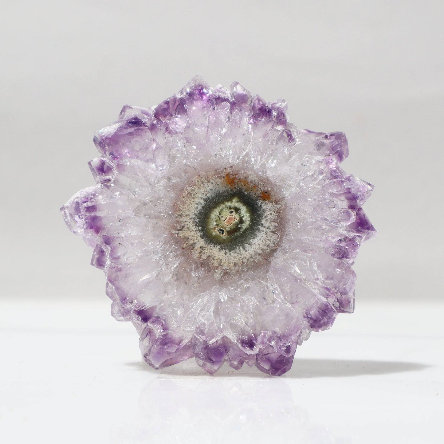 This classy Uruguayan amethyst stalactite slice offers us a perfect flower of quartz crystals outlined in delicate purple with a center of green jasper and a detail of red hematite.