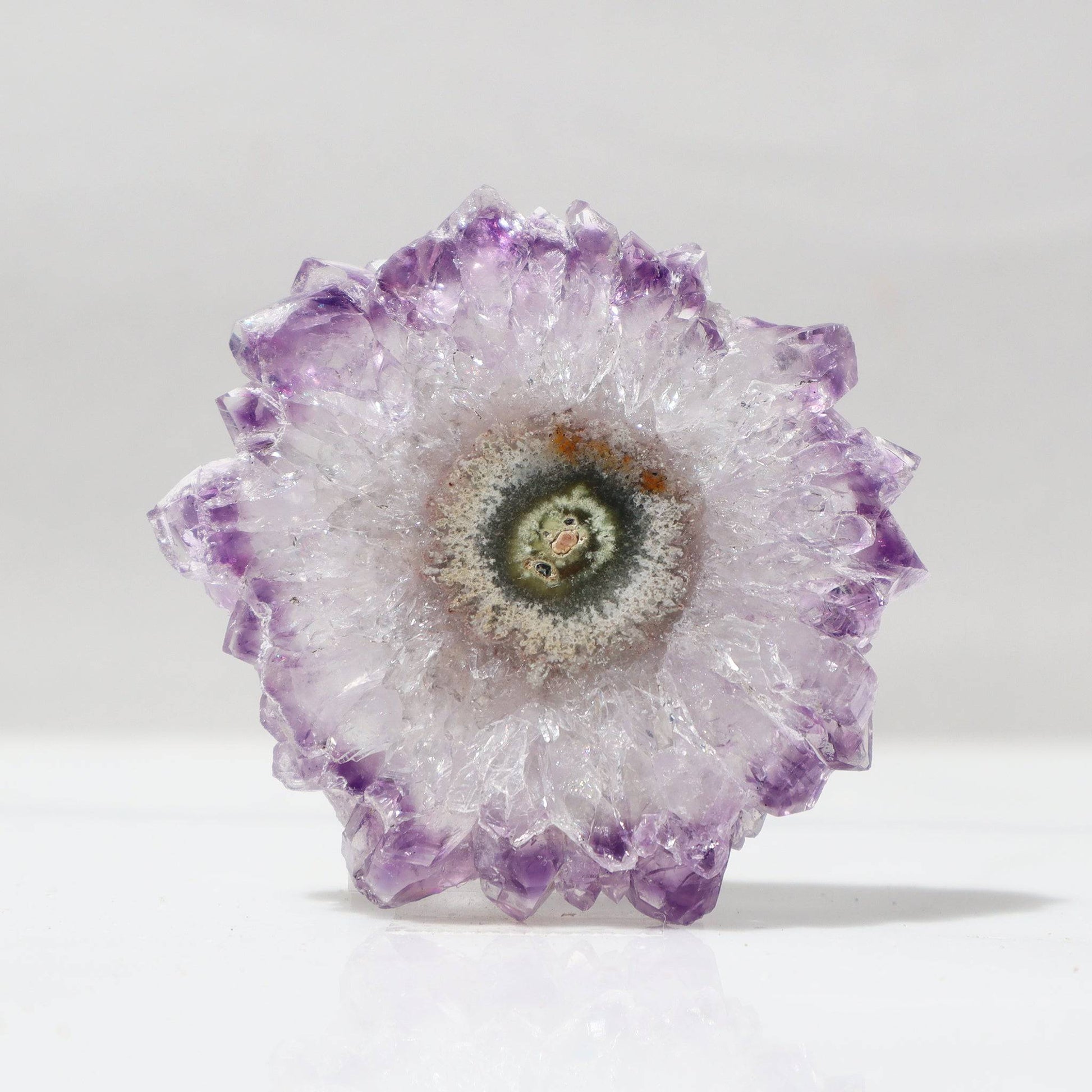 This classy Uruguayan amethyst stalactite slice offers us a perfect flower of quartz crystals outlined in delicate purple with a center of green jasper and a detail of red hematite.