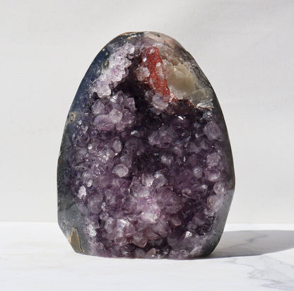 Purple crystals, delicate calcite formation, and the involvement of a rare red hematite quartz formation, all framed by a thick see-through green celadonite band, beautiful stalactite formations