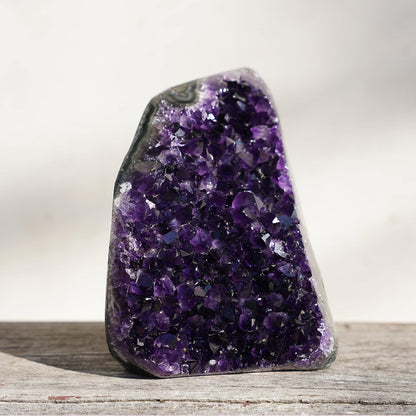 Three-dimensional purple amethyst geode with a window in the rough basalt back from which to peek through into the mix of minerals involved in the formation process. Exposing a display of quartz in the back.